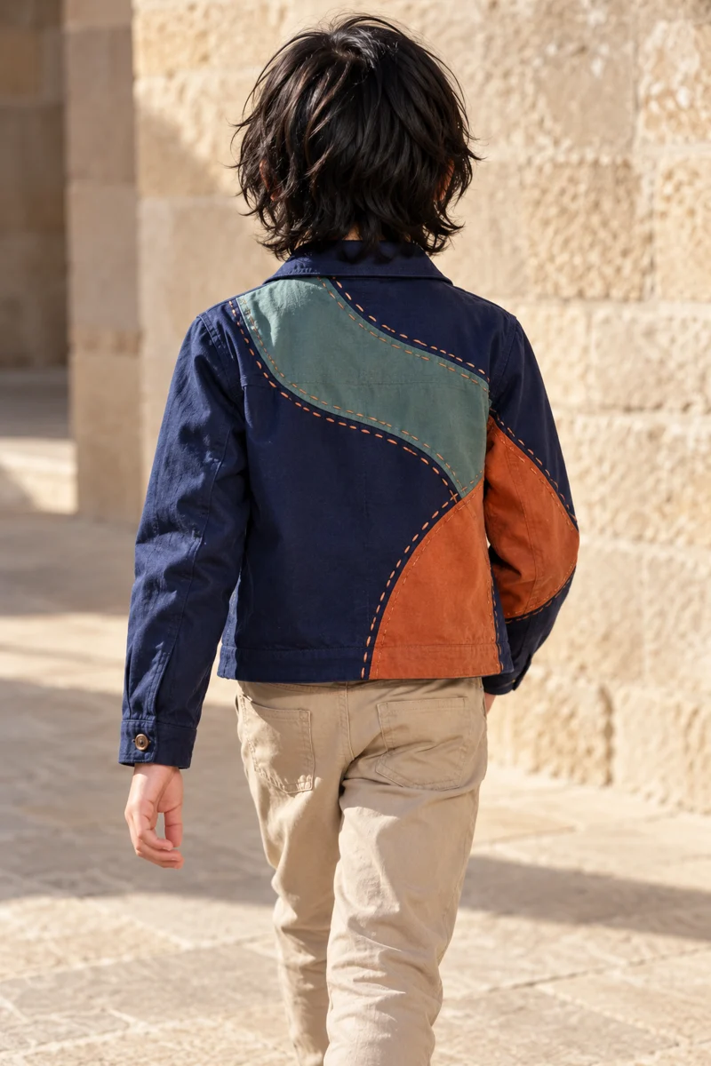 Rear view of a navy jacket with hand-sewn teal and rust panels