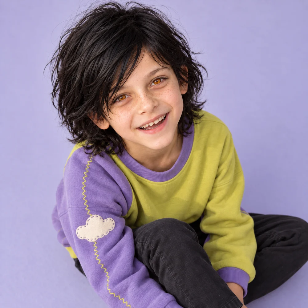 Playful grin, freckles and black hair in a lime and lavender sweatshirt