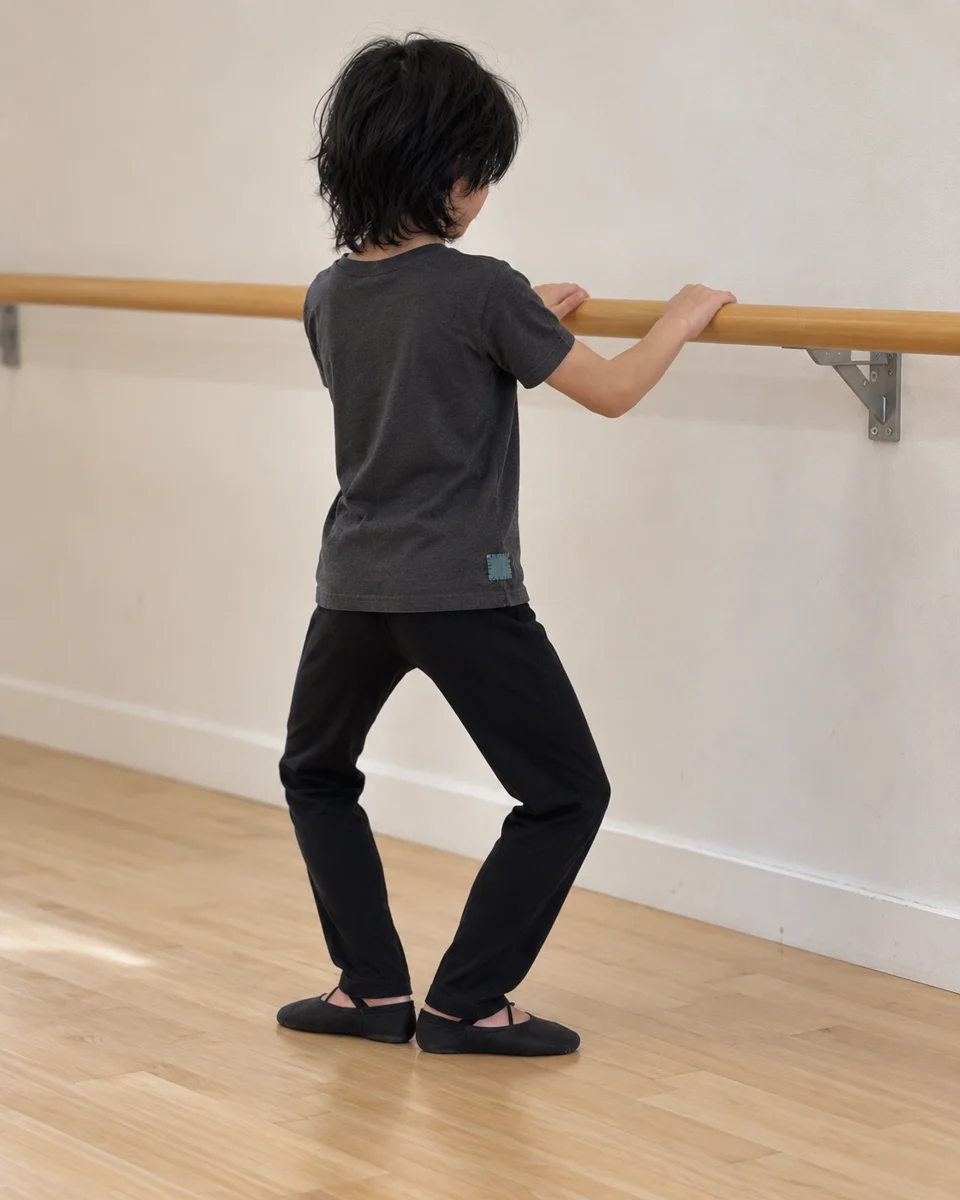 From behind at a ballet barre, pausing between practice exercises in comfortable dance clothes